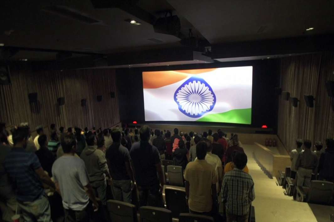 People singing national anthem in a cinema hall
