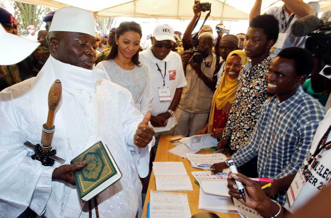Gambian President Yahya Jammeh holds a copy of the Quran while speaking to a poll worker at a polling station during the presidential election in Banjul, Gambia, December 1, 2016, Reuters/UNI