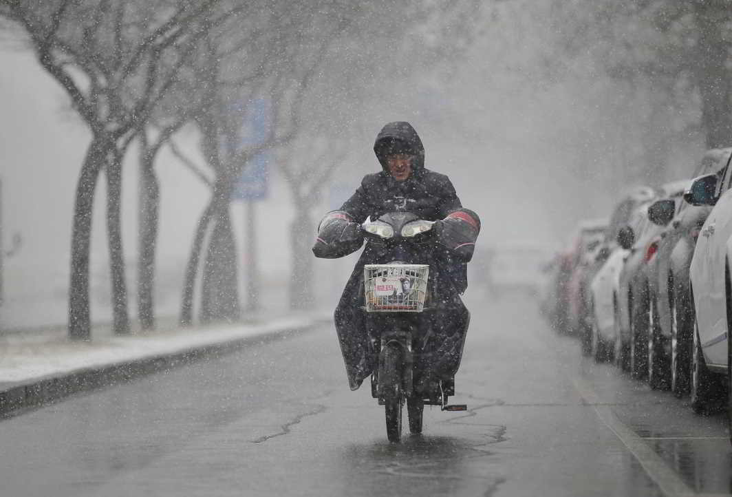 THROUGH THE HAZE: A man rides an electric bicycle during a snowfall in Beijing, Reuters/UNI