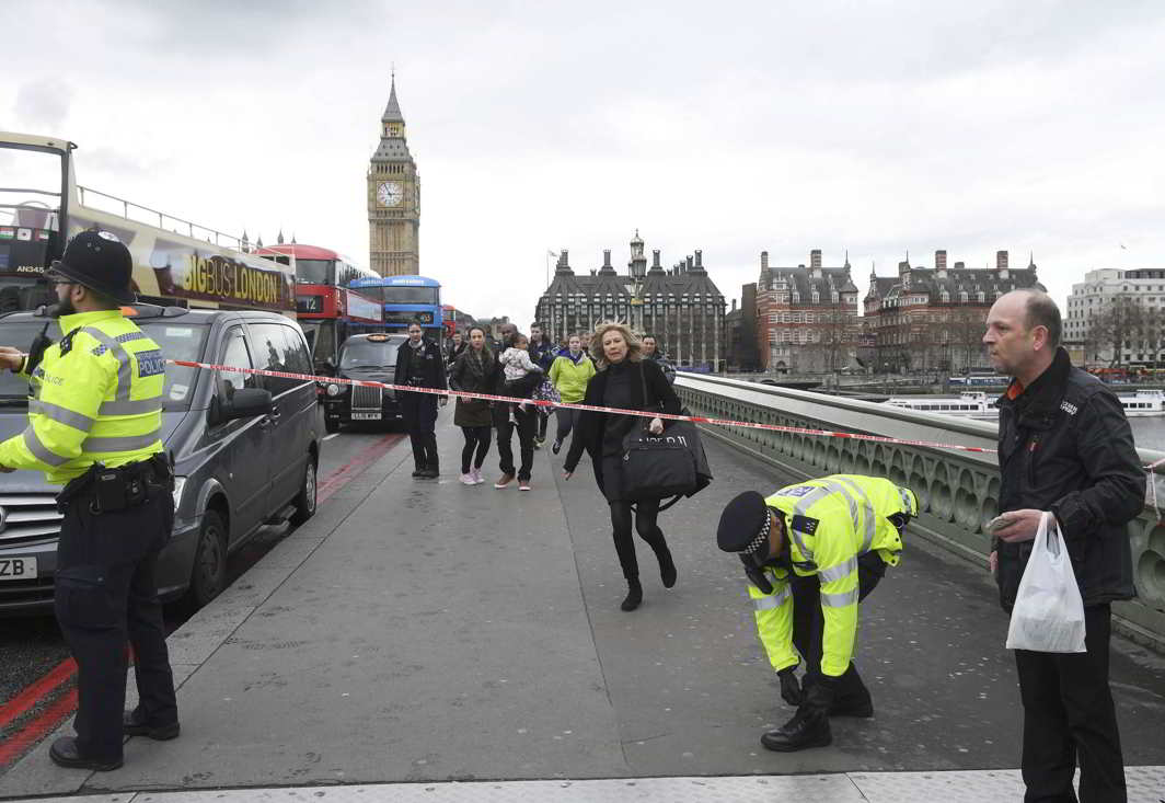 A woman ducks under police tape on Westminster Bridge after the attack