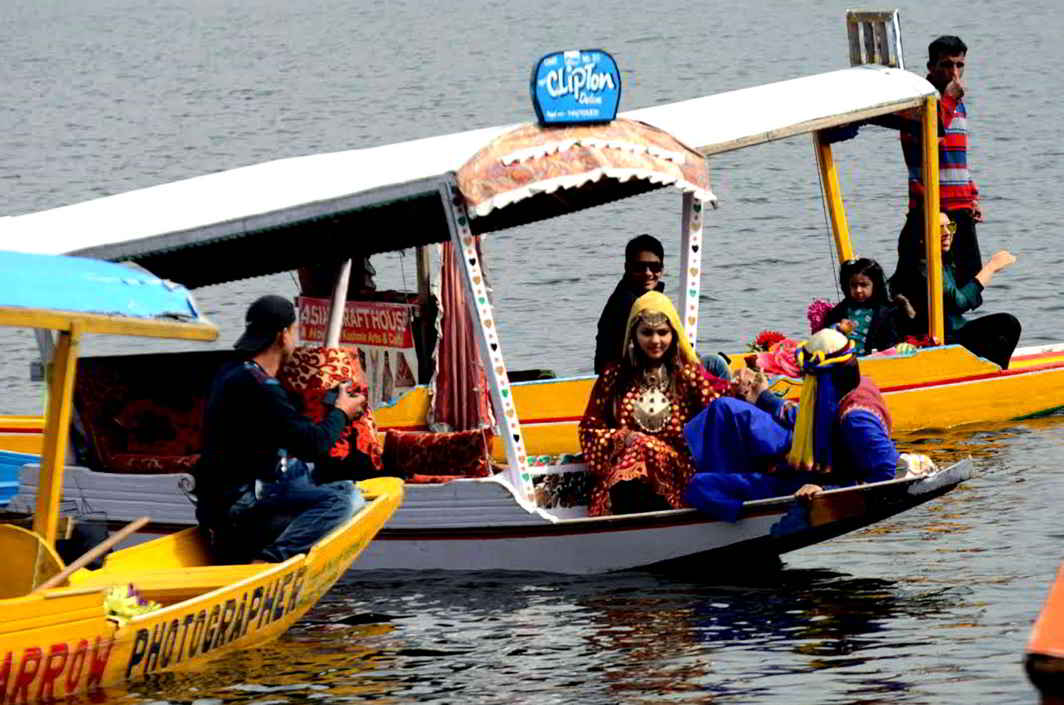 BOAT TALES: Tourists on a shikara in the world famous Dal Lake in Srinagar, attired in traditional Kashmir dress, pose for a memorable photograph. UNI