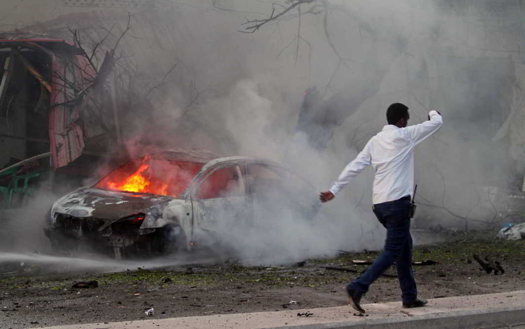 SUICIDE STRIKE: A Somali man walks past the wreckage of a burning vehicle at the scene of an attack where a car laden with explosives rammed into a cafeteria in capital Mogadishu, Reuters/UNI