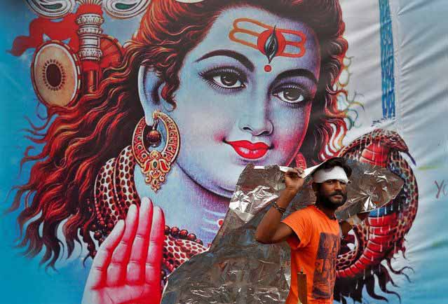 SHIVA’S LOYAL: A kanwaria shelters from the rain in front of a poster of Lord Shiva in New Delhi, Reuters/UNI