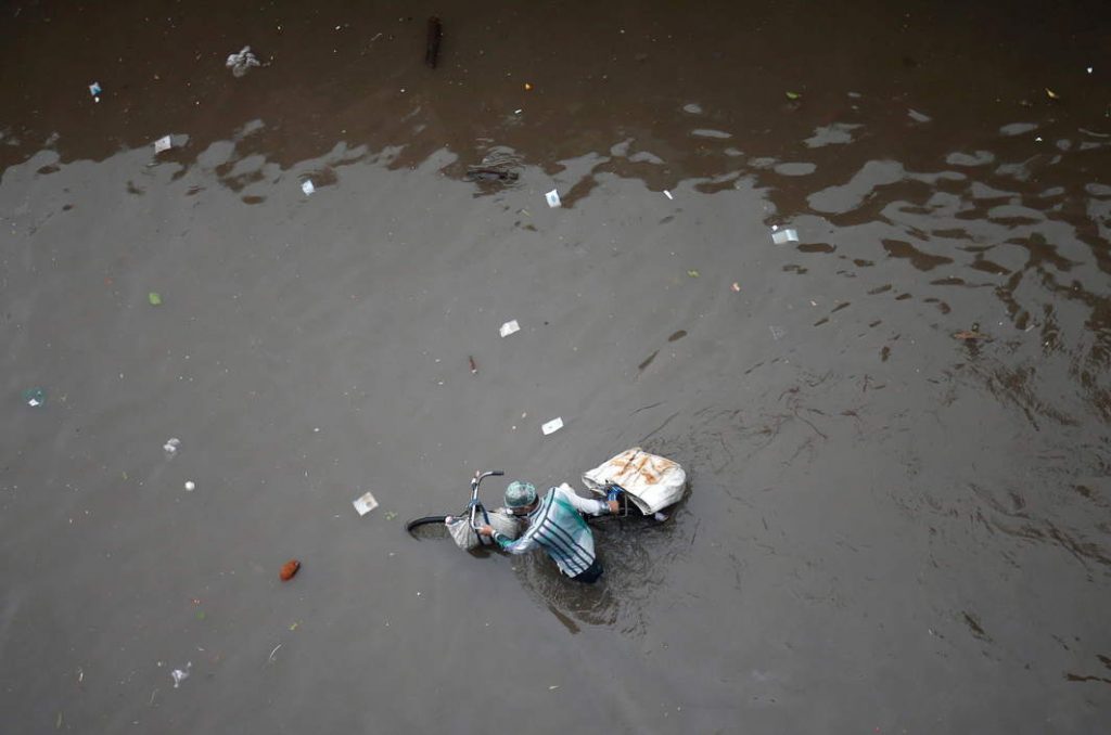 NATURE THE TEACHER: A man pushes his bicycle through a water-logged street after heavy rains in Ahmedabad, Reuters/UNI