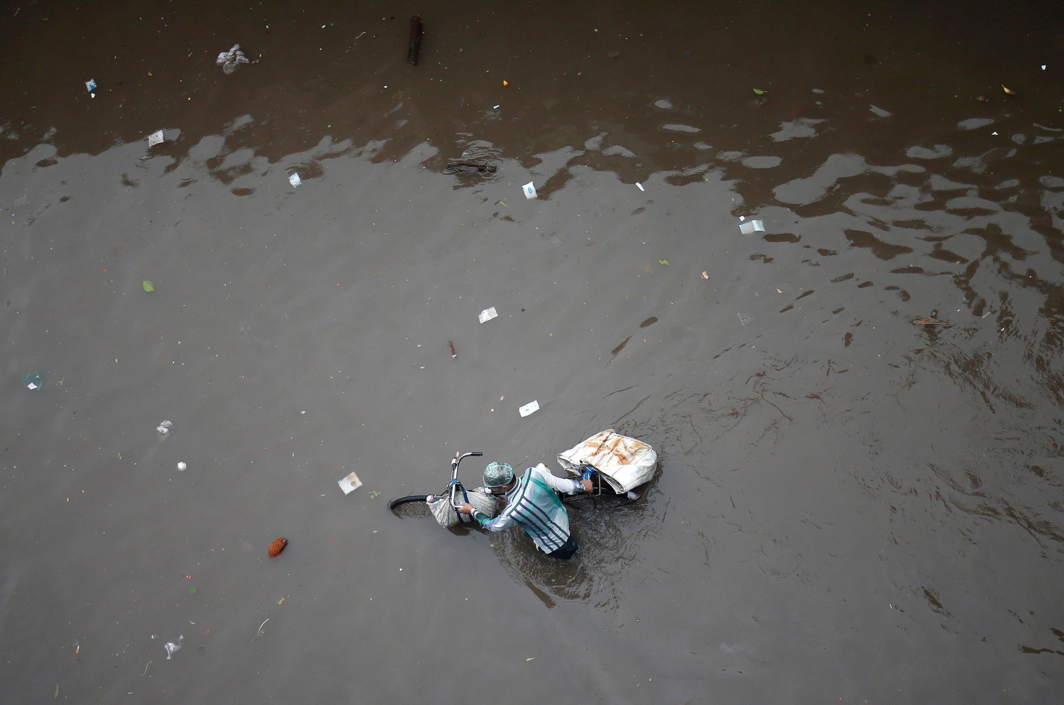 NATURE THE TEACHER: A man pushes his bicycle through a water-logged street after heavy rains in Ahmedabad, Reuters/UNI
