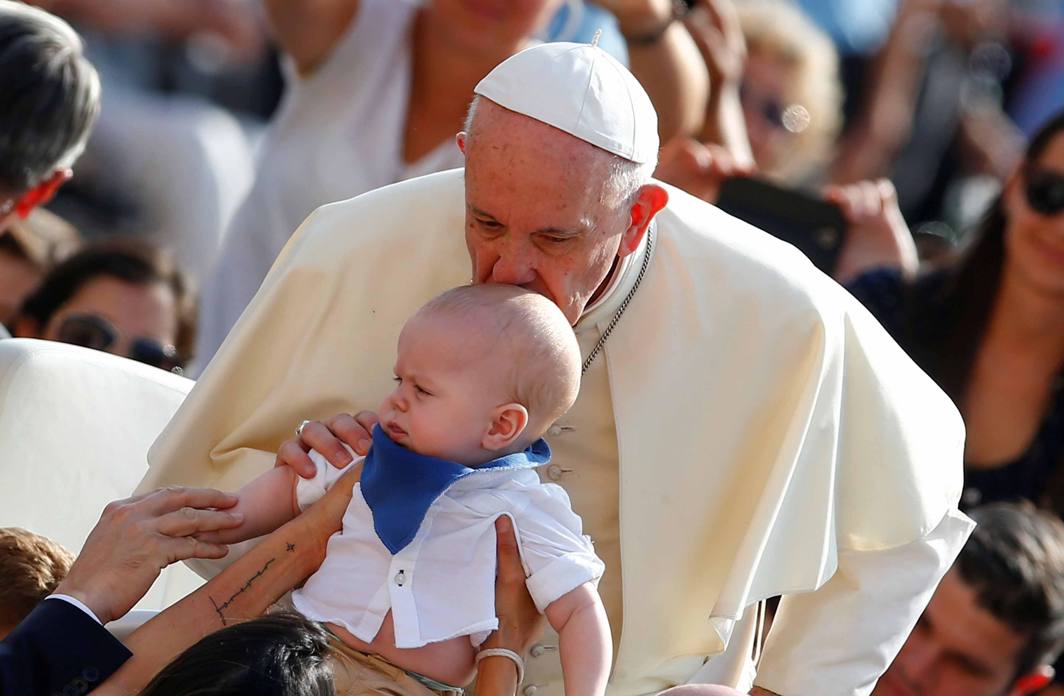 RECEIVING LOVE: Pope Francis kisses a baby as he arrives to lead his Wednesday general audience in Saint Peter's Square at the Vatican, Reuters/UNI