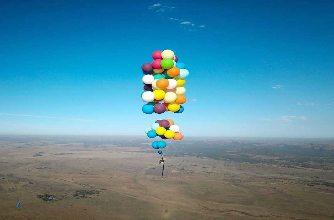 PRETTILY RISKING: Tom Morgan, from Bristol-based company The Adventurists, flies in a chair with large party balloons tied to it near Johannesburg, South Africa, The Adventurists and Richard Brandon Cox/Reuters/UNI