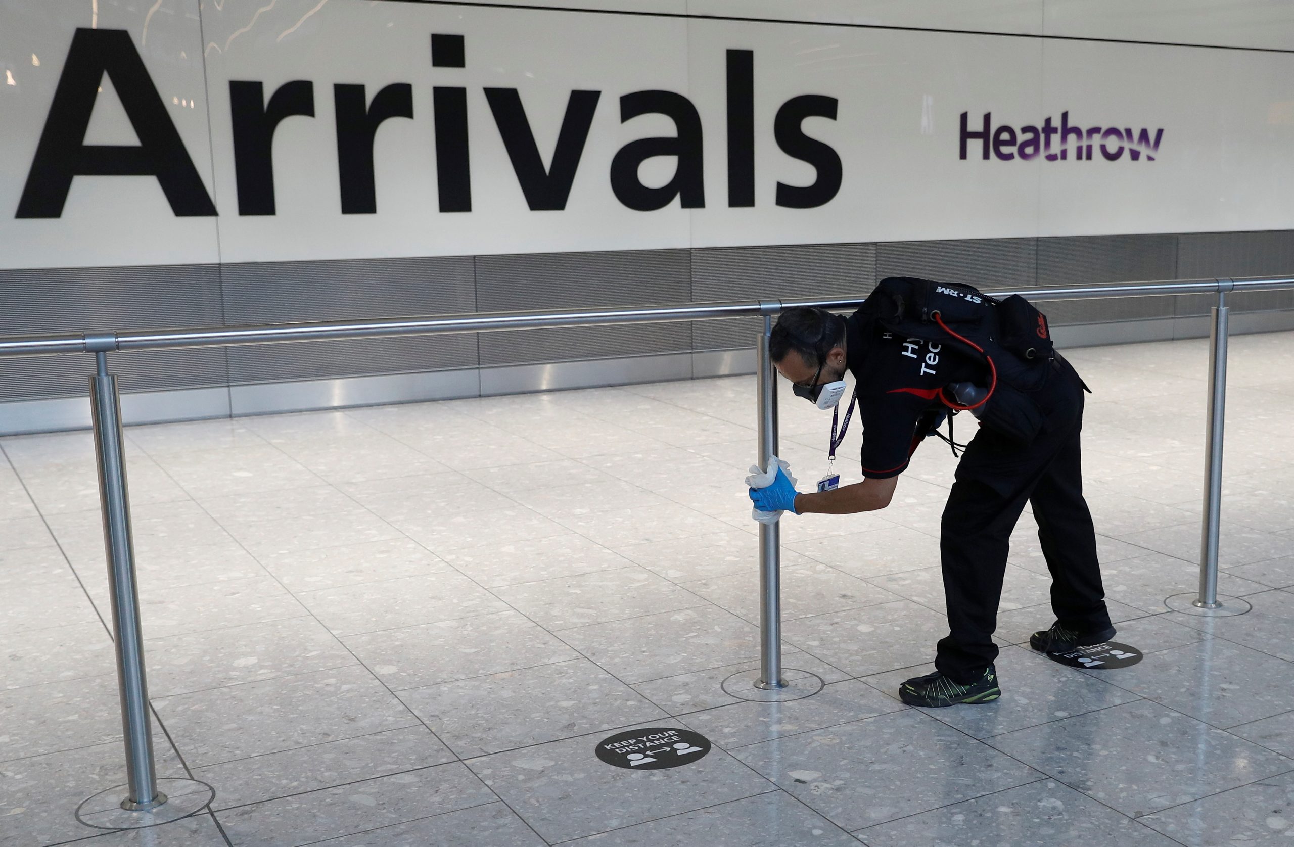 A worker sanitises a barrier at the International arrivals area of Terminal 5 in London's Heathrow Airport
