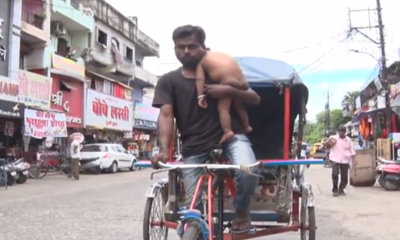 man carries infant in his hands while riding rickshaw