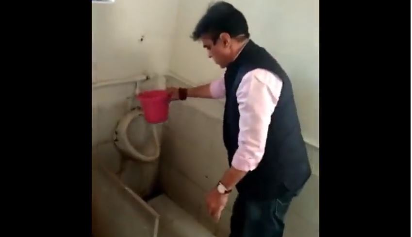 Education Minister Praful Panseria cleans school's dirty toilet