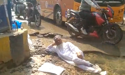 Man lies in water-logged pothole on road