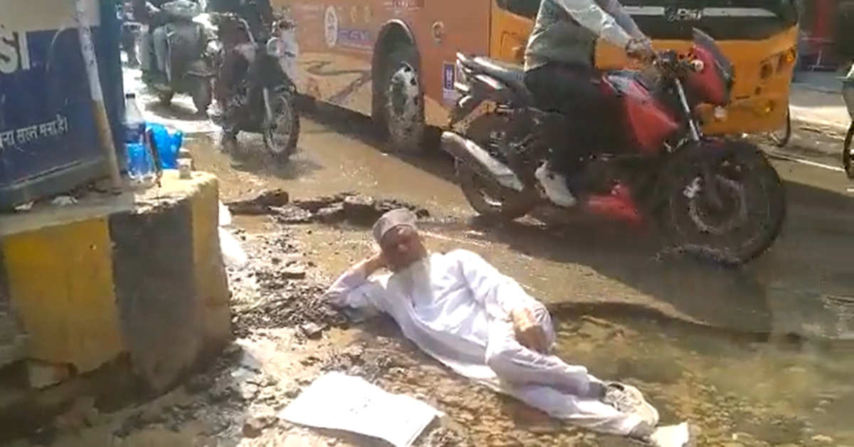 Man lies in water-logged pothole on road