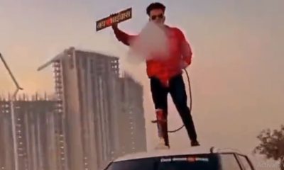 man standing atop car, smoking hookah